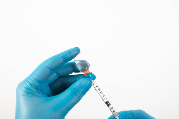 COVID-19 coronavirus vaccine. Vaccination concept. Doctor's hand in blue gloves hold medicine vaccine vial bottle and syringe. - Fotoğraf, Görsel