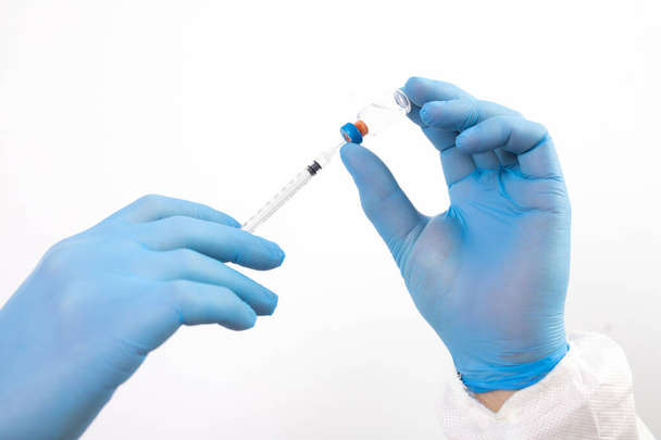COVID-19 coronavirus vaccine. Vaccination concept. Doctor's hand in blue gloves hold medicine vaccine vial bottle and syringe.  - Foto, imagen