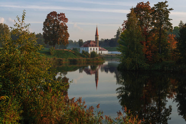 View of the Priory Palace on the shore of the Black Lake on an autumn sunny evening with clouds, Gatchina, St. Petersburg, Russia - Valokuva, kuva