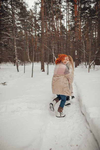 Δύο κορίτσια διασκεδάζουν στο χειμερινό δάσος. Υψηλής ποιότητας φωτογραφία - Φωτογραφία, εικόνα