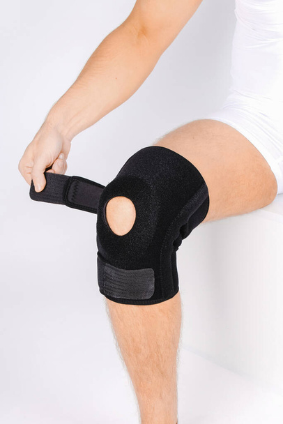 Knee Support Brace on leg isolated on white background. Elastic orthopedic orthosis. Anatomic braces for knee fixation, injuries and pain. Protective knee joint bandage sleeve. Trauma, rehabilitation - Zdjęcie, obraz