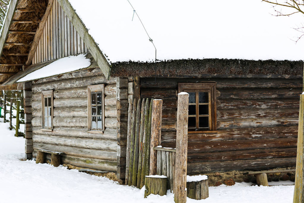 Rus kışı manzarası. Eski ahşap bir kulübe, sazdan çatılı ahşap bir ev. Karla kaplı terk edilmiş bir Rus köyü. Ahırlı ahşap ev. - Fotoğraf, Görsel