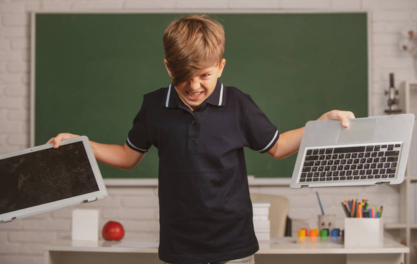 Bad boy student vs distance education. Angry kid broken online laptop at school. Smashing damaged computer technology. Kids problem with remote learning. - 写真・画像