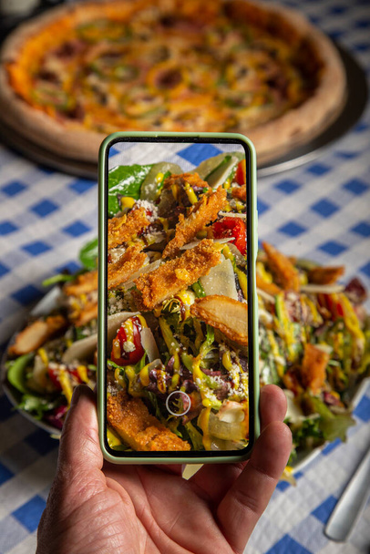 Blogger de comida usando um smartphone tirando fotos de uma salada leve em um restaurante italiano para compartilhar nas mídias sociais - Foto, Imagem