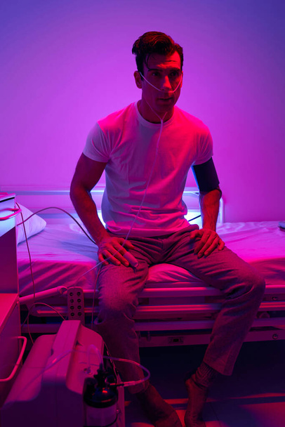 Dospělý muž sedí v místnosti s růžovým světlem - Fotografie, Obrázek