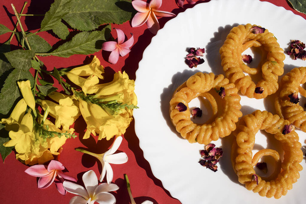 Dulces Imarti, popular plato dulce de la India. Postre circular en forma de espiral hecho con harina de urad dal y jarabe de azúcar como Jalebi. Imarti sobre fondo festivo decorado con flores - Foto, imagen