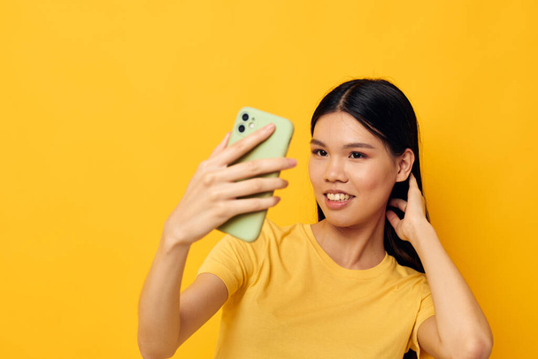 Portrait Asian beautiful young woman in a yellow t-shirt looking at the phone posing Lifestyle unaltered - Foto, Imagen