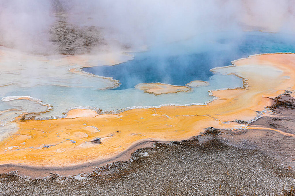 Hot zone of blue and orange minerals in geyser with sulphur smoke inside Yellowstone National park, Γουαϊόμινγκ, Ηνωμένες Πολιτείες. - Φωτογραφία, εικόνα