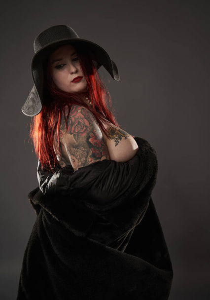 Beautiful tattooed plus size woman in black fur and hat, glamour shot - Foto, afbeelding