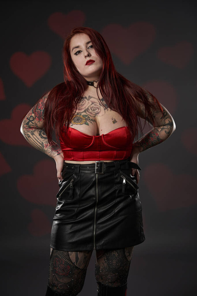 Schöne tätowierte große (plus size) Frau mit Tätowierungen in schwarzem Rock und rotem BH, Inklusivität und Körperpositivität - Foto, Bild