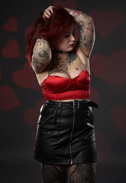 Beautiful tattooed large (plus size) woman with tattoos in black skirt and red bra, inclusiveness and body positivity - Photo, Image