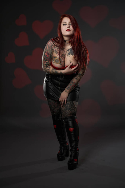 Beautiful tattooed large (plus size) woman with tattoos in black skirt and red bra, inclusiveness and body positivity - Fotó, kép