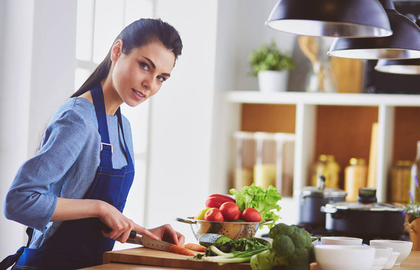 Young woman cutting vegetables in kitchen at home - Foto, Imagen