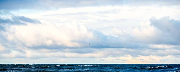 Kumlu bir sahilden (kum tepeleri) Baltık denizinin panoramik görüntüsü. Koyu bulutlu dramatik bir gökyüzü. Dalgalar, su sıçramaları. Idyllic deniz manzarası. Sıcak kış havası, iklim değişikliği, doğa - Fotoğraf, Görsel