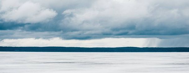 Bulutlu bir günde donmuş orman gölü. Kar fırtınasından sonra dramatik bir gökyüzü. Onega, Karelia, Rusya. Atmosferik kış manzarası. Panoramik manzara. Doğa, iklim değişikliği, Noel tatilleri, eko turizm - Fotoğraf, Görsel