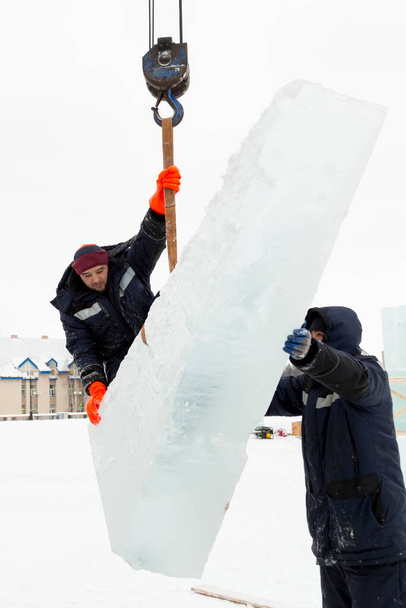 Ο εγκαταστάτης στέκεται στο μπλοκ πάγου κρατώντας την ταινία σφεντόνα - Φωτογραφία, εικόνα