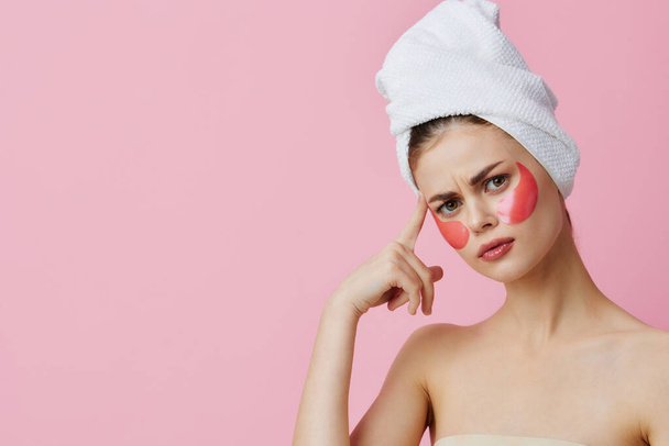 woman pink patches on the face with a towel on the head pink background - Φωτογραφία, εικόνα