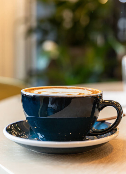 Coffee in a blue cup on a wooden table in cafe or coffee shop. Morning. Lifestyle. Blurred background. - Foto, imagen