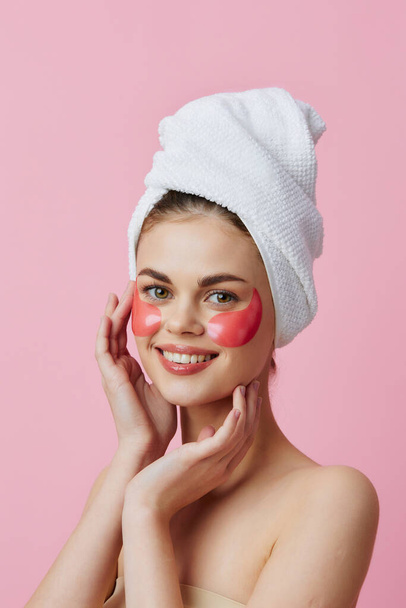 mooie vrouw huidverzorging gezicht pleisters kale schouders roze achtergrond - Foto, afbeelding