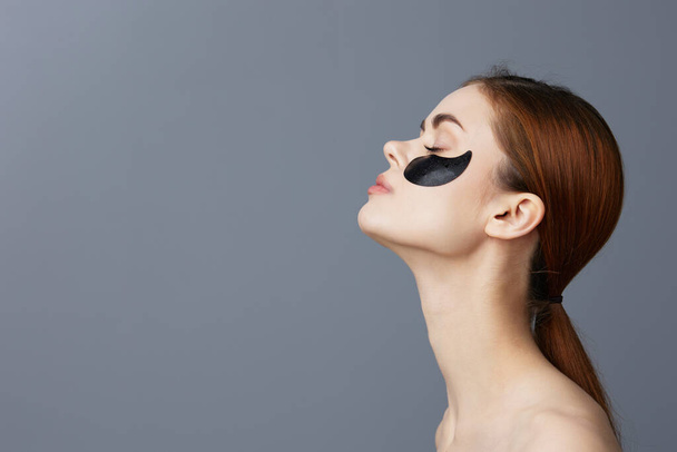 vrouw oog vlekken op gezicht blote schouders huidverzorging geïsoleerde achtergrond - Foto, afbeelding