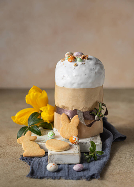 Easter composition with traditional Orthodox sweet bread. Kulich with meringue icing, candy shaped eggs, easter cookies and tulip. - Fotoğraf, Görsel
