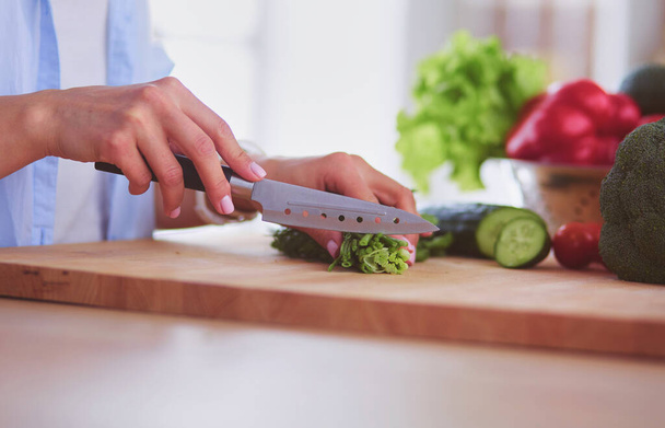 Young woman cutting vegetables in kitchen at home. - Foto, imagen