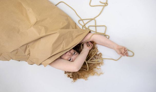 half unwrapped cute sexy redhead mature woman in valentine gift surprise package, wrapped in wrapping paper and string rope, copy space - Fotó, kép