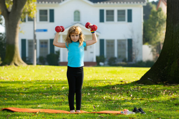 Child boy working out with dumbbells on park background. Kids sport outdoor. - Valokuva, kuva
