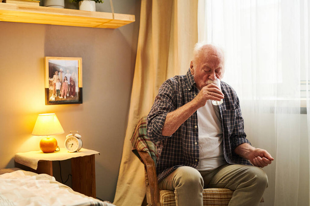 Senior man drinking pills in the morning - Фото, зображення