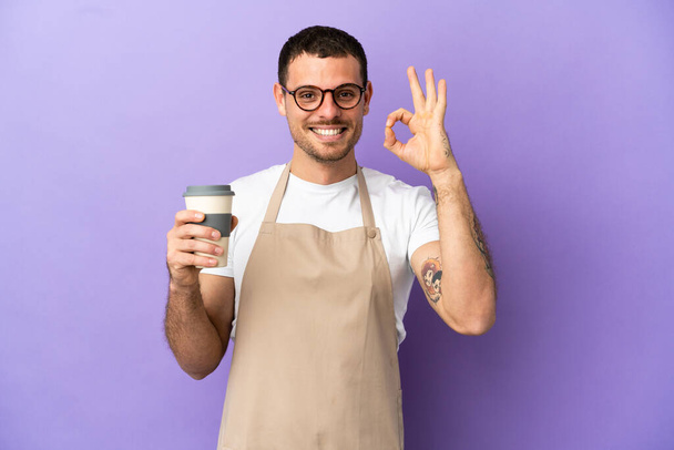 Camarero de restaurante brasileño sobre fondo púrpura aislado mostrando ok signo con los dedos - Foto, imagen