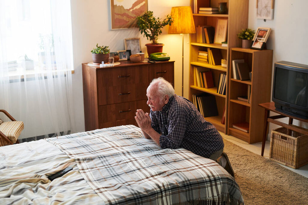 Ηλικιωμένος θρησκευόμενος άντρας προσεύχεται στην κρεβατοκάμαρα - Φωτογραφία, εικόνα