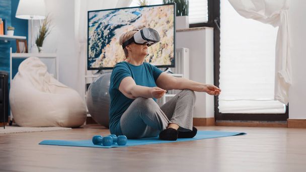Retired woman meditating in lotus position with vr glasses - Foto, afbeelding