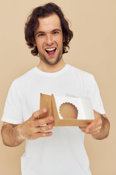 emotional man with gift small box on beige background - Фото, зображення