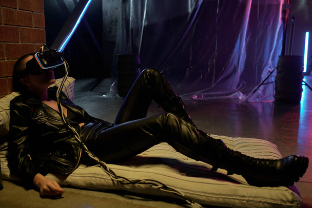 Young cyberpunk female in black leather clothes and vr headset - Фото, зображення