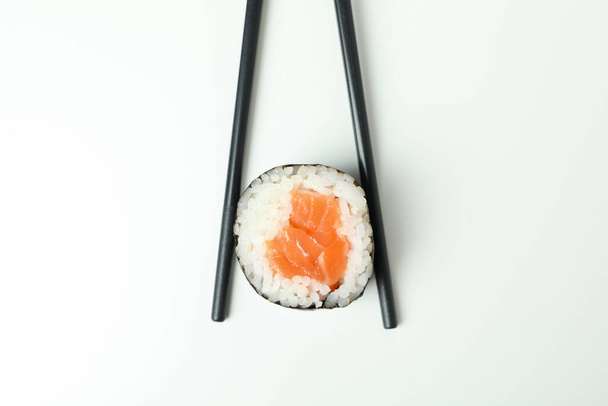 Chopsticks with maki on white background, close up - Foto, afbeelding