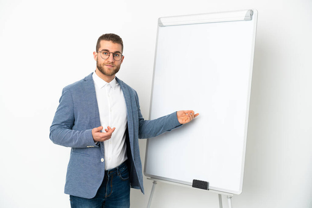 Jonge knappe blanke man geïsoleerd op witte achtergrond geven van een presentatie op witte boord - Foto, afbeelding