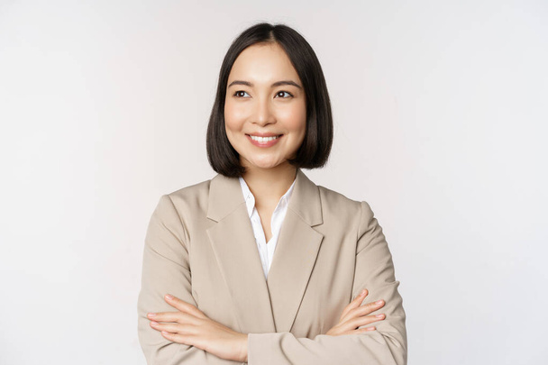 Уверенная женщина-предприниматель, азиатская деловая женщина, стоящая у власти, профессиональный бизнесмен, скрещенные руки на груди, стоя на белом фоне - Фото, изображение