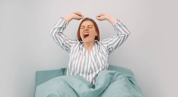 Красива молода щаслива біла жінка розтягується після пробудження в ліжку вранці
. - Фото, зображення