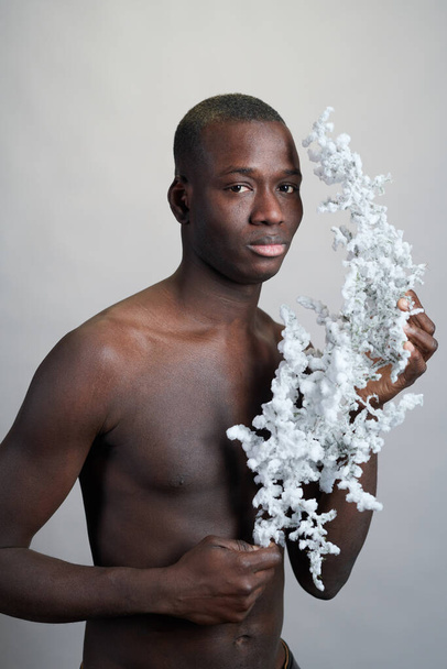 Muž bez košile afrického etnika držící kvetoucí větev - Fotografie, Obrázek