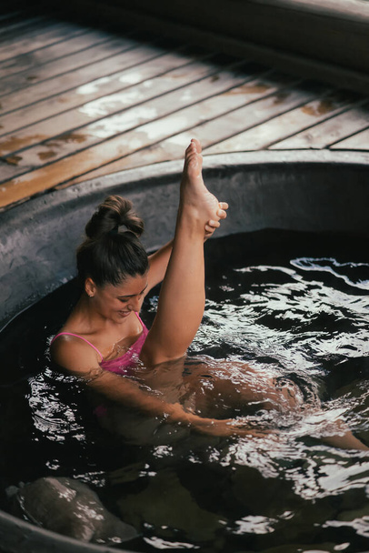 Woman relaxing in round outdoor bath. Organic skin care in hot bath - Photo, Image