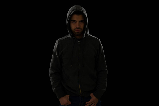 Dangerous thief. Angry young man with a black hoodie looking suspicious and scary during a dark night - Φωτογραφία, εικόνα