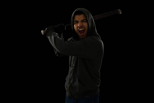 Violent hispanic thug using a baseball bat to hit a victim and screaming while looking at the camera - Фото, изображение