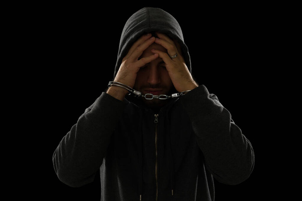 Smutný mladý muž a zloděj s rukama na tváři s lítostí při nošení pout po krádeži   - Fotografie, Obrázek