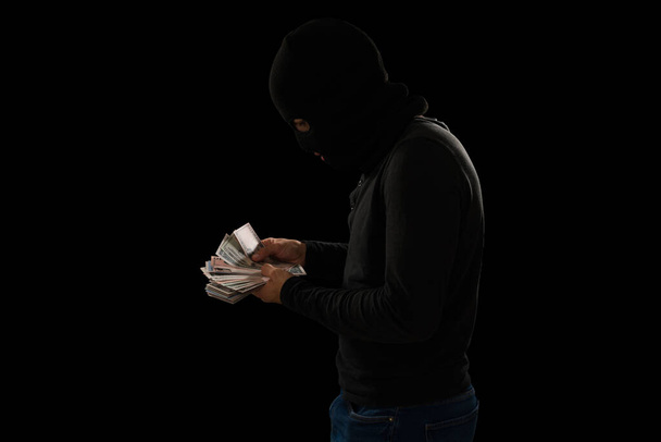 Profile of male thief and criminal in his 20s counting the stolen money after a robbery  - Foto, Imagen