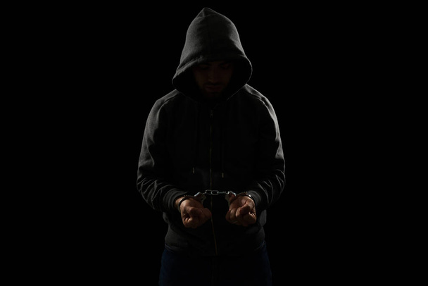Молодий чоловік одягнений в светр і в наручники після арешту за крадіжку і скоєння злочину
 - Фото, зображення