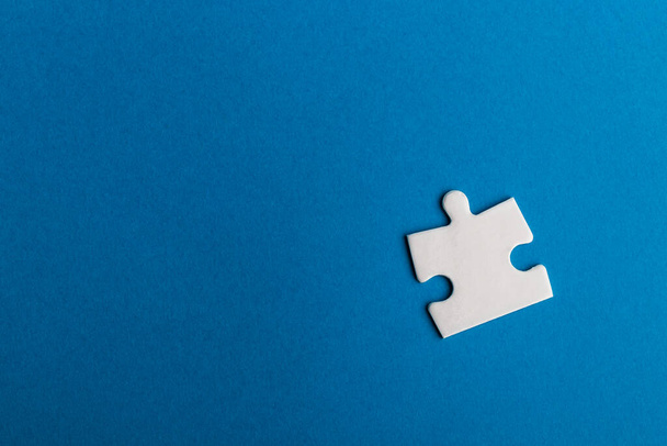 White jigsaw puzzle piece on blue background. Texture photo with space for text. - Zdjęcie, obraz