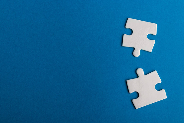 White jigsaw puzzle pieces on blue background. Texture photo with space for text. Teamwork conceptual photo. - Photo, Image