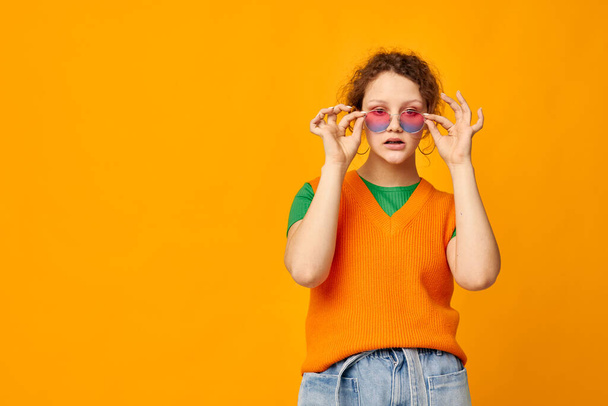 beautiful woman orange sweatshirts sunglasses multicolored glasses supply yellow background unaltered - Valokuva, kuva