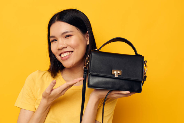 smiling asian woman woman handbag fashion yellow background - Фото, изображение