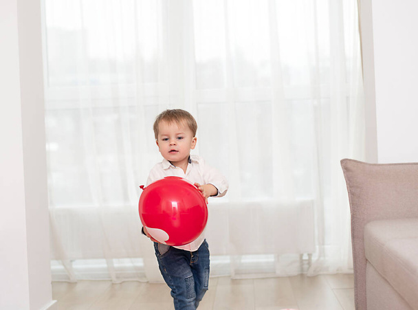 lindo niño pequeño con globos blancos y rojos en casa. Concepto de San Valentín. Enfoque suave. - Foto, Imagen